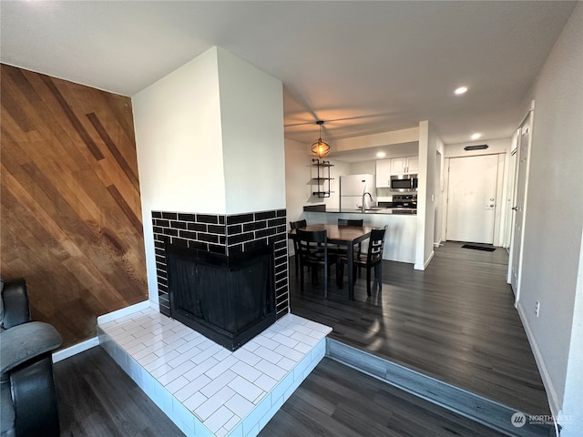 dining room with wood walls, dark hardwood / wood-style flooring, and sink