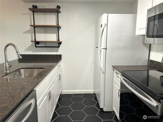 kitchen with dark tile patterned floors, white cabinetry, sink, and appliances with stainless steel finishes