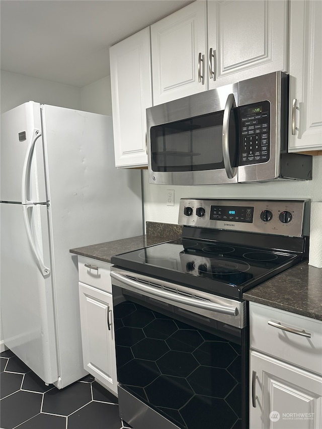 kitchen with white cabinets, stainless steel appliances, and dark tile patterned floors