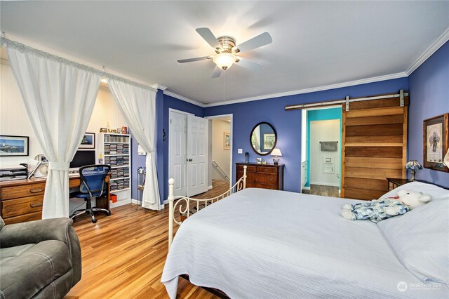 bedroom with a barn door, ceiling fan, crown molding, and light hardwood / wood-style floors