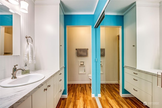 bathroom featuring hardwood / wood-style floors, vanity, toilet, and ornamental molding