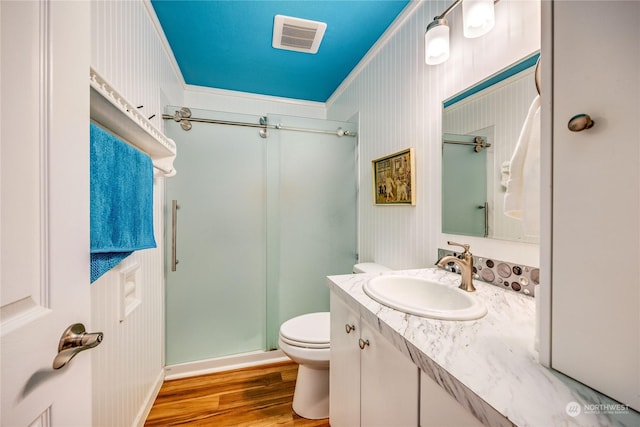 bathroom featuring walk in shower, ornamental molding, vanity, hardwood / wood-style flooring, and toilet