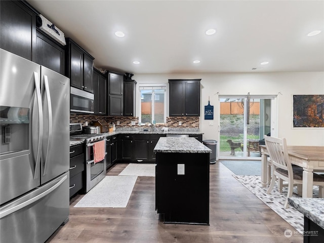 kitchen featuring light stone countertops, dark hardwood / wood-style flooring, a center island, and stainless steel appliances