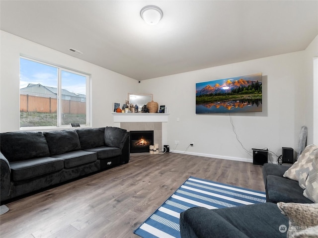 living room with hardwood / wood-style floors and a tiled fireplace