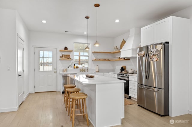 kitchen with a center island, white cabinetry, premium range hood, and stainless steel appliances