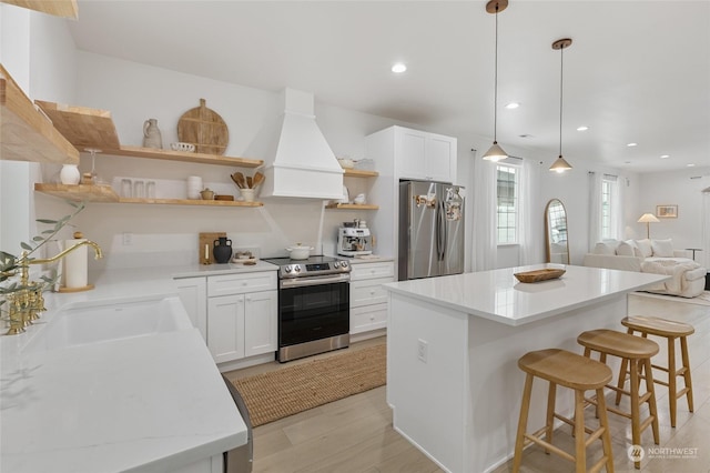 kitchen featuring white cabinetry, sink, hanging light fixtures, appliances with stainless steel finishes, and custom exhaust hood