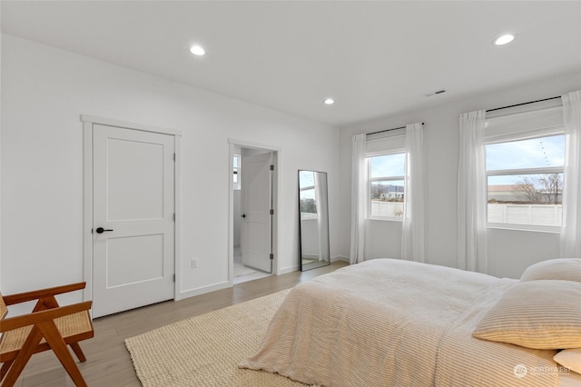 bedroom with ensuite bathroom and light wood-type flooring