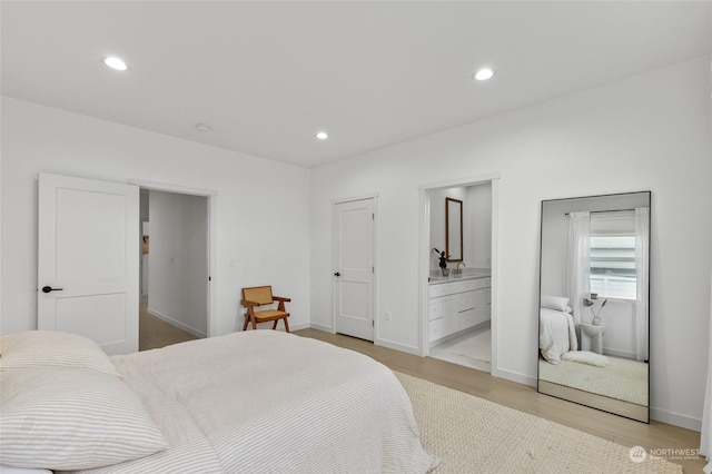 bedroom featuring ensuite bath and light wood-type flooring