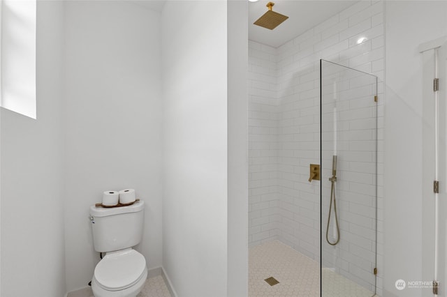 bathroom with a tile shower and toilet