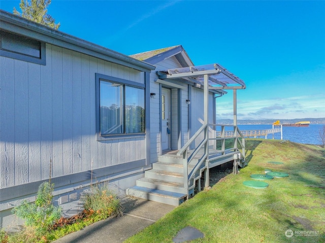 view of exterior entry featuring a yard and a water view