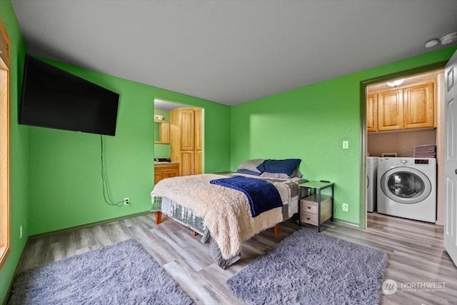 bedroom with light wood-type flooring and separate washer and dryer