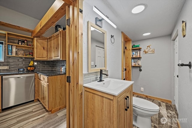 kitchen with backsplash, sink, dishwasher, and light hardwood / wood-style flooring