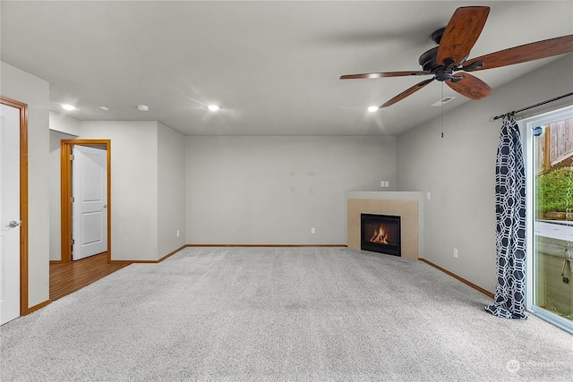 unfurnished living room with a tiled fireplace, ceiling fan, and carpet