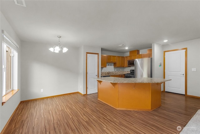 kitchen featuring a chandelier, a center island, decorative light fixtures, light hardwood / wood-style floors, and appliances with stainless steel finishes