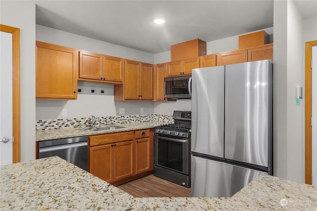 kitchen with stainless steel appliances, decorative backsplash, sink, and light stone counters