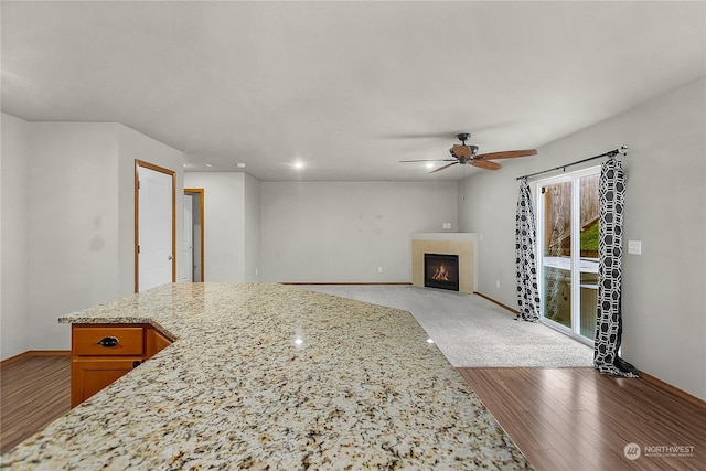 living room with ceiling fan, hardwood / wood-style floors, and a tile fireplace