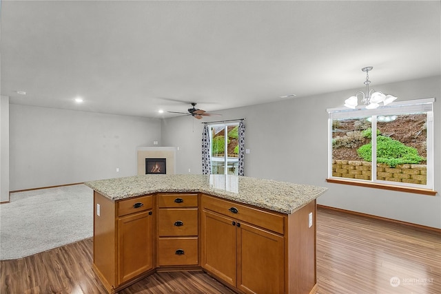 kitchen with ceiling fan with notable chandelier, a kitchen island, hanging light fixtures, and light hardwood / wood-style flooring