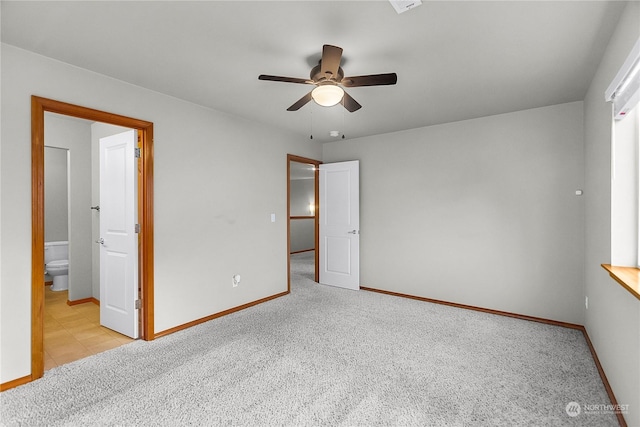 unfurnished bedroom featuring ensuite bath, light colored carpet, and ceiling fan