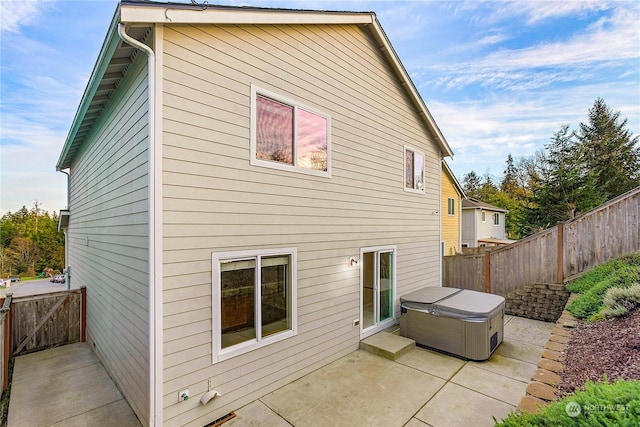 back of property with a patio and a hot tub