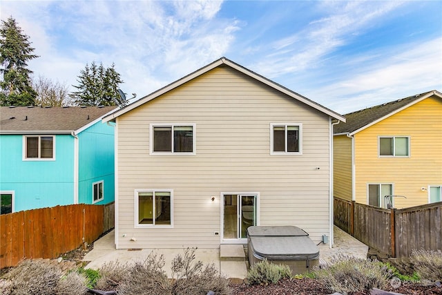 rear view of property featuring a patio and a hot tub