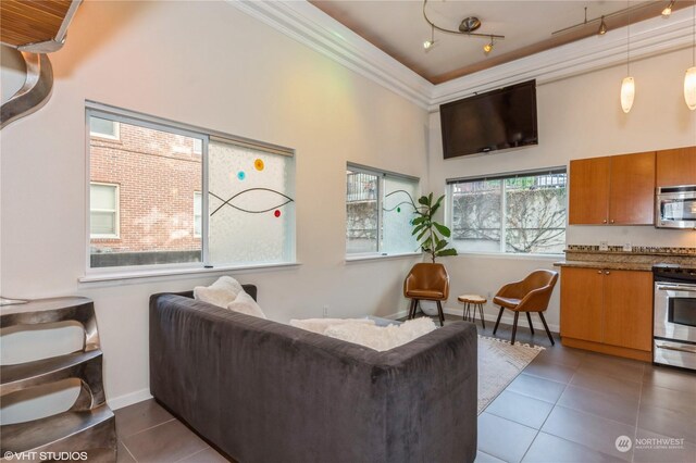 living room featuring a towering ceiling, dark tile patterned floors, and crown molding