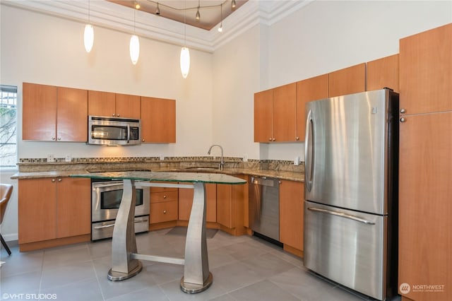 kitchen with hanging light fixtures, a towering ceiling, a tray ceiling, light tile patterned flooring, and appliances with stainless steel finishes