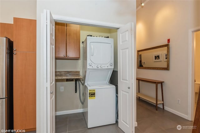 laundry room featuring tile patterned flooring, ornamental molding, and stacked washer / dryer