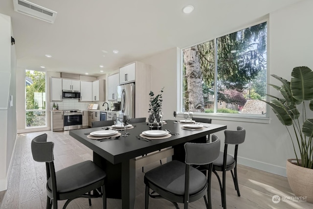 dining area featuring light wood-type flooring, a wealth of natural light, and sink