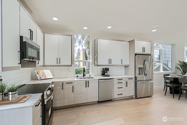 kitchen featuring white cabinets, light wood-type flooring, sink, and appliances with stainless steel finishes