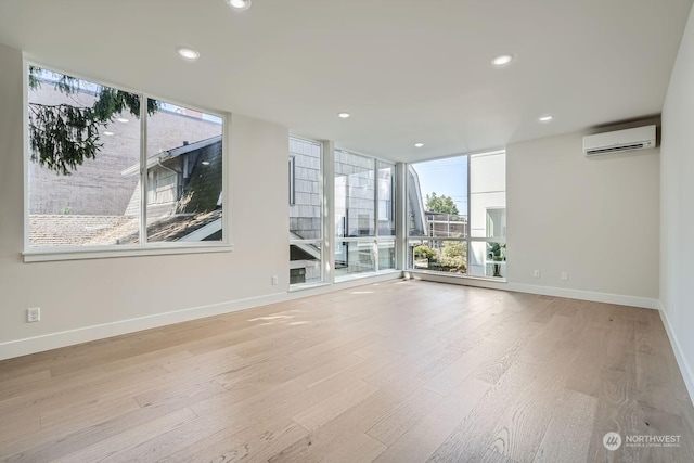 spare room featuring a healthy amount of sunlight, light hardwood / wood-style floors, and a wall mounted AC