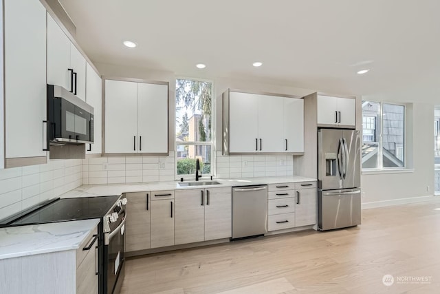 kitchen with white cabinets, appliances with stainless steel finishes, light hardwood / wood-style floors, and sink