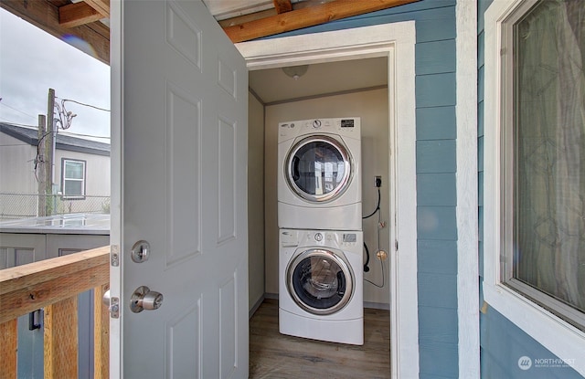 laundry room featuring dark hardwood / wood-style flooring and stacked washer and dryer