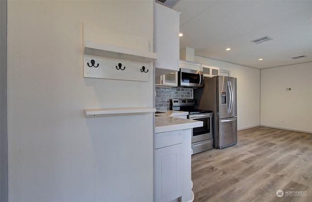 kitchen with light hardwood / wood-style floors, white cabinetry, and stainless steel appliances