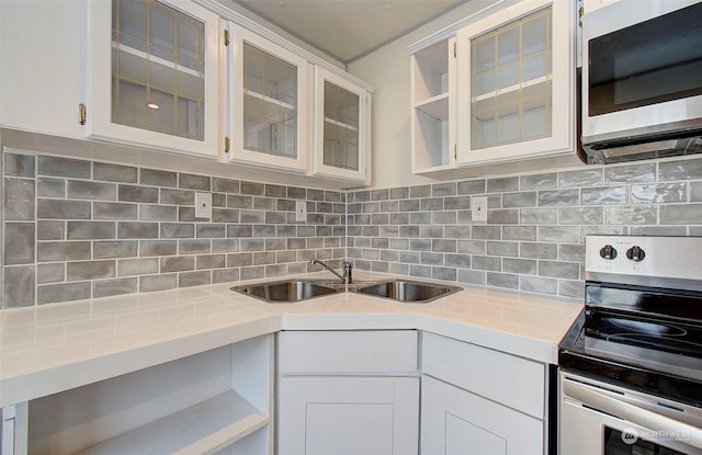 kitchen with appliances with stainless steel finishes, backsplash, white cabinetry, and sink