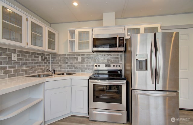 kitchen with tasteful backsplash, white cabinetry, light hardwood / wood-style flooring, and stainless steel appliances