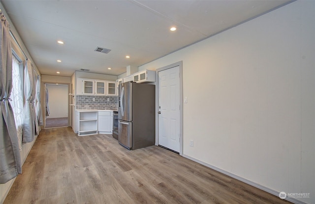 kitchen featuring white cabinets, appliances with stainless steel finishes, light hardwood / wood-style floors, and tasteful backsplash