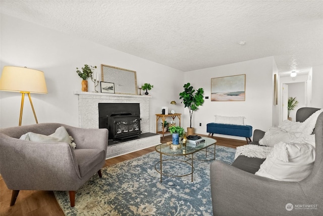 living room with hardwood / wood-style floors, a wood stove, and a textured ceiling