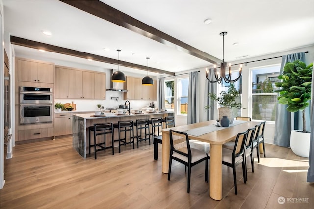 dining space with beam ceiling, sink, light hardwood / wood-style floors, and a notable chandelier