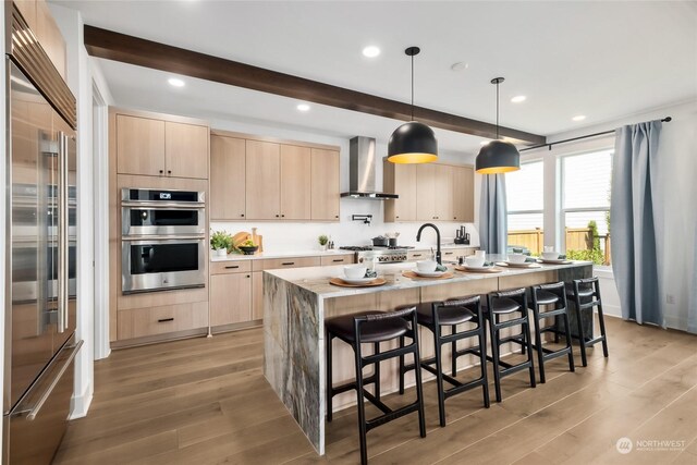 13734 SE 84th St Unit 14, Newcastle, WA 98059 - kitchen featuring stainless steel appliances, light brown cabinetry, wall chimney range hood, light wood-style flooring, and beam ceiling