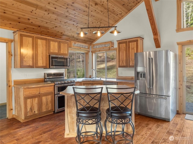 kitchen with a wealth of natural light, hanging light fixtures, a kitchen island, wood ceiling, and appliances with stainless steel finishes