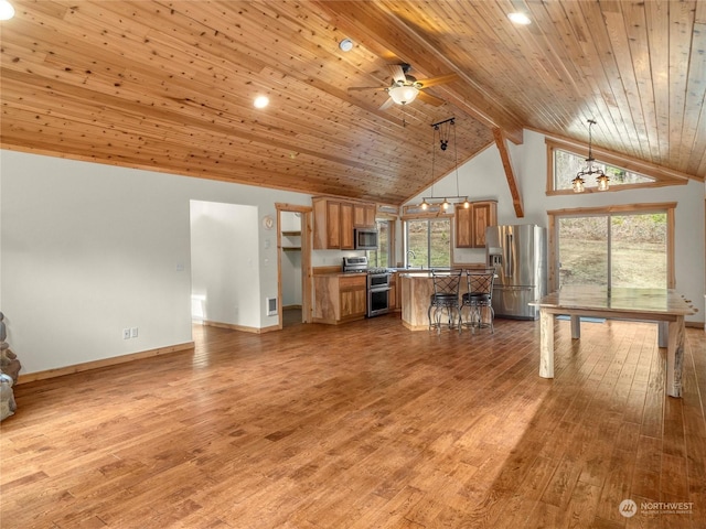 kitchen featuring beamed ceiling, ceiling fan with notable chandelier, pendant lighting, wood ceiling, and appliances with stainless steel finishes