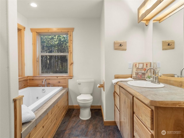 bathroom with toilet, vanity, a relaxing tiled tub, and hardwood / wood-style flooring