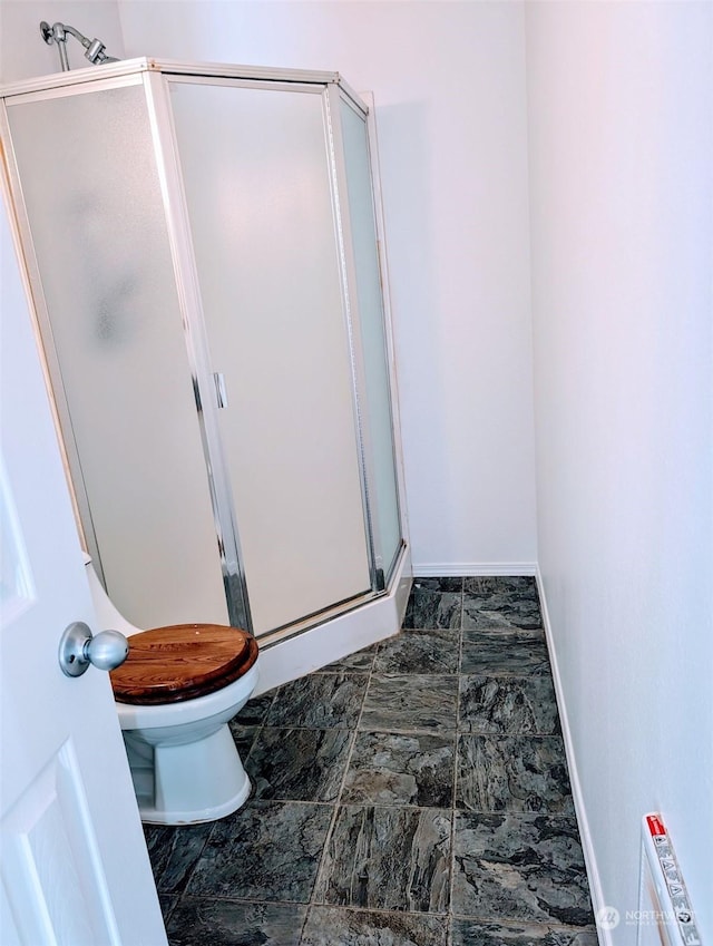 full bathroom with baseboards, a shower stall, and toilet