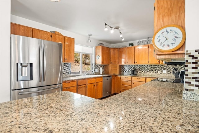 kitchen featuring tasteful backsplash, light stone countertops, sink, and appliances with stainless steel finishes