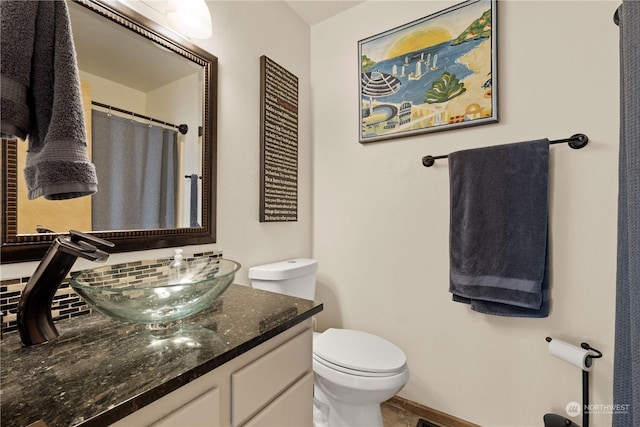 bathroom with decorative backsplash, vanity, and toilet