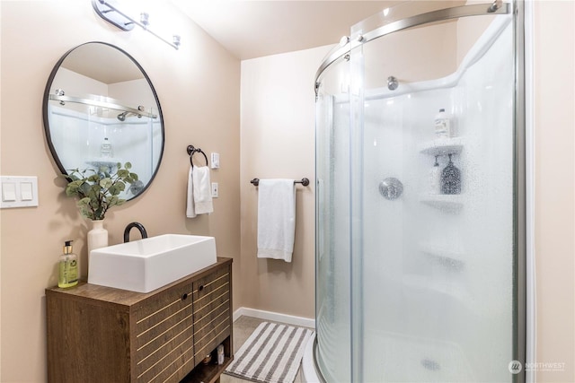 bathroom featuring a shower stall, baseboards, and vanity