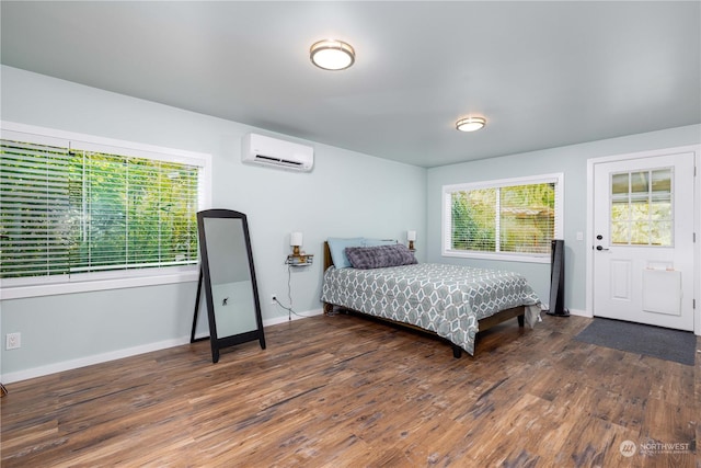 bedroom with a wall mounted AC, wood finished floors, and baseboards