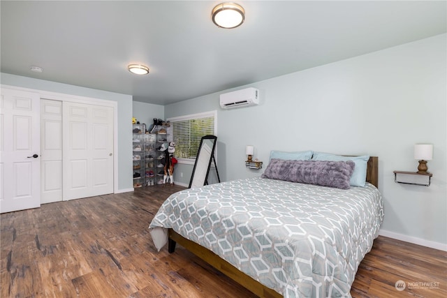 bedroom with a closet, an AC wall unit, baseboards, and wood finished floors