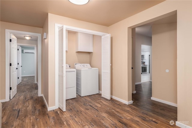 clothes washing area with a wall mounted air conditioner, dark hardwood / wood-style floors, washer and clothes dryer, and cabinets