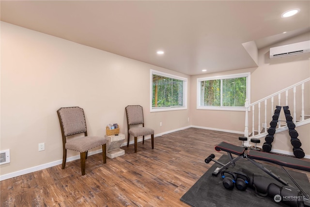 exercise room with recessed lighting, an AC wall unit, baseboards, and wood finished floors